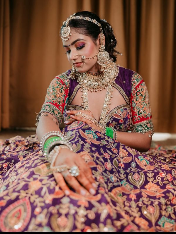 Bride in purple embroidered lehenga with kundan jewellery and green bangles